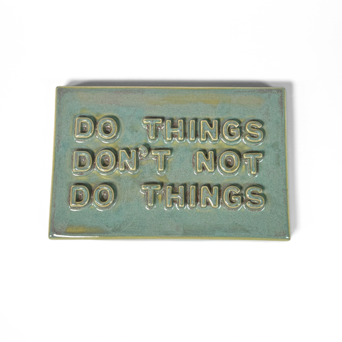 A rectangular ceramic sign with the embossed text 'DO THINGS DON'T NOT DO THINGS' in a teal-green glaze, shown on a plain white background.